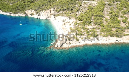 Aerial drone bird's eye view photo of emerlald and sapphire clear water rocky beach found in mediterranean island covered with pine trees