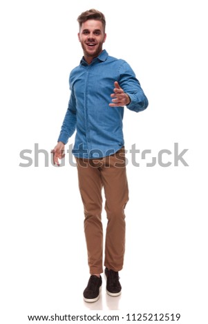 excited young casual man stepping on white background wants you to choose, full length picture