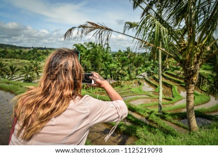 Woman takes picture with a smartphone on rice terrace,  on Bali streets, Indonesia