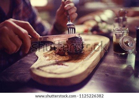 steak in the restaurant on the table / dinner in the restaurant, meat on the plate, served steak and cutlery Royalty-Free Stock Photo #1125226382