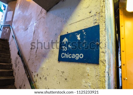 A sign pointing up a set of stairs towards Chicago.