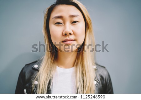 Half length portrait of young charming serious asian woman dressed in casual clothes spending time near to promotional background.Close up view  of beautiful female with clear skin face and no make up