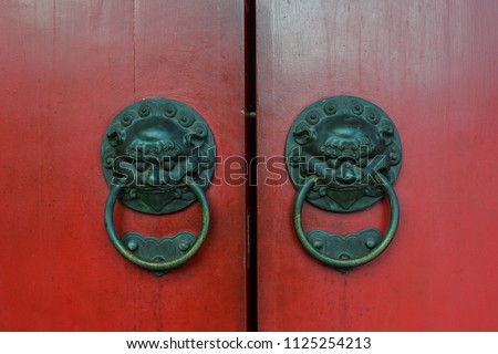 Old bronze knocker with red door in Chinese temple.