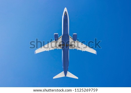 medium size blue passenger airplane on a clear sky background. bottom view a few seconds before landing. composition photography. flying overhead to destination airport. travel and journey concept.