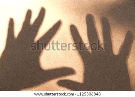 Black silhouette on white sand, open the palm of the hand symbol