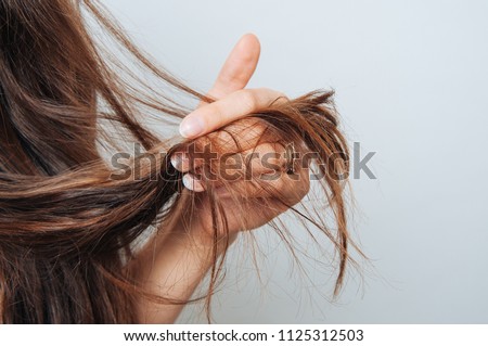 Girl holding her hair in her hand. Hair care concept. Shampoo. Haircut needed.  Royalty-Free Stock Photo #1125312503
