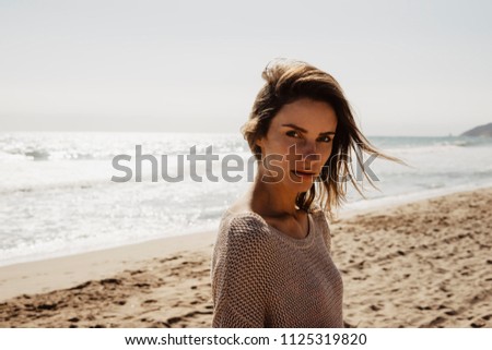 portrait young pretty girl looking on summer beach, hipster in sand coastline on background seascape horizon blue sun ocean, beauty model posing in jacket in nature outdoors, relax lifestyle concept