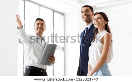 real estate business, sale and people concept - happy smiling realtor with folder showing customers new office room Royalty-Free Stock Photo #1125321749