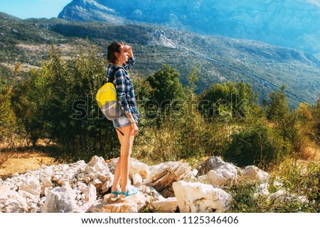 Beautiful girl with a briefcase stands against the mountains