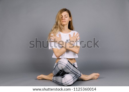 Sporty beautiful young woman practicing yoga, working out wearing grey and white sportswear, studio