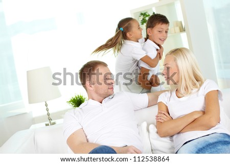 Portrait of young couple looking at one another with two children playing on background