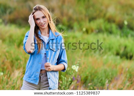 Happy young girl wearing blue jeans jacket in the field