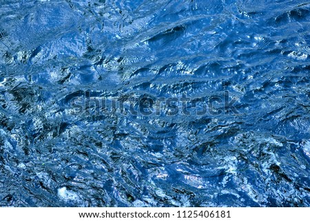 Background blue waves of the sea. The sea blue waves, raging, are broken against the rocks