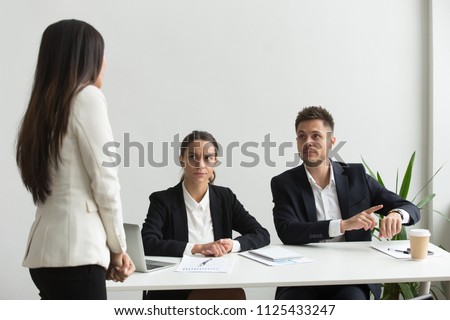 Angry executive pointing at wristwatch scolding unpunctual tardy employee for delay, missing deadline or being late at team meeting, bad time management, discipline and punctuality at work concept Royalty-Free Stock Photo #1125433247