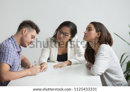 Unhappy married family couple getting divorced in asian attorney lawyers office, husband signing decree paper giving permission to marriage annulment dissolution, divorce settlement concept Royalty-Free Stock Photo #1125433331