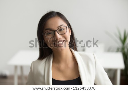 Smiling asian woman in glasses for vision correction looking at camera, happy friendly chinese student or employee posing in office, millennial japanese woman professional head shot portrait Royalty-Free Stock Photo #1125433370