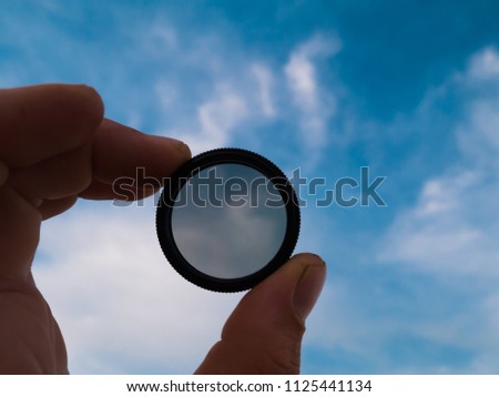 Light filter in hand against sky background
