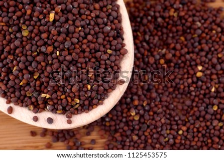 Black (brown) indian mustard seeds (Brassica Koch) in wooden spoon, copy space. Healthy nutrition, cosmetics, herbal medicine concept. Food  photography. Top view, flat lay