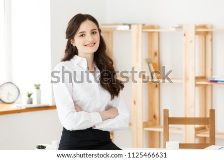 Portrait of young beautiful business woman in the office. Smilling and Crossed arms.