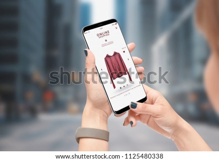 Girl shopping online with phone while walking on the city street