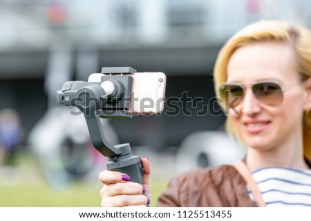 the girl with the phone on the stabilizer leads the videoblog. She takes herself to the camera Smartphone