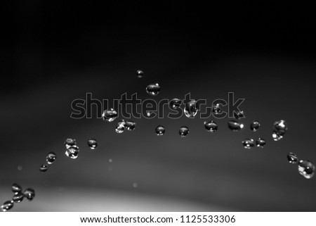 Close-up of water drops forming an arc on dark background
