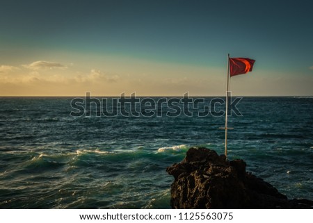 Red flag at in front of the ocean