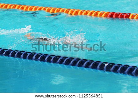 Water splash from young swimmer swims in the swimming pool