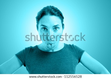 Young woman portrait who is pulling her tongue out tinted in blue