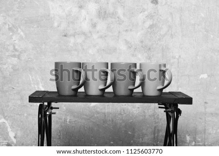 Modern low table with four caps of tea or coffee near wall. Cozy home and cookware concept. Table with colourful cups on wall background. Coffee table and bright stylish cups of different colours.