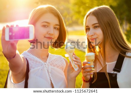 two beautifu best girlfriends schoolgirls ( student) do selfie on the phone in the park