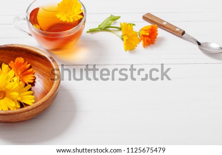 Calendula (Marigold) herbal tea  on white wooden table