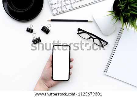 Flat lay of top view Business woman use smartphone on modern white desk work table with computer laptop and stationary in home office includes copyspace for add text or graphic