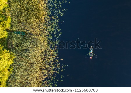 Top down aerial view of small rowing boat near coast of lake in Moletai region, Lithuania Royalty-Free Stock Photo #1125688703