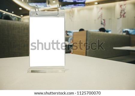 Mockup empty white label menu frame on table with cafe restaurant interior background