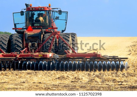 red tractor for harvesting in the midst of the summer season, produces disk field