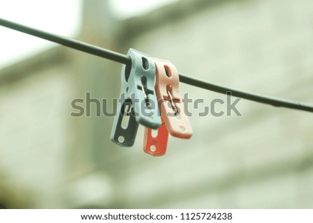 Two plastic clothespins on a rope on the background of a brick wall of house. Selective focus
