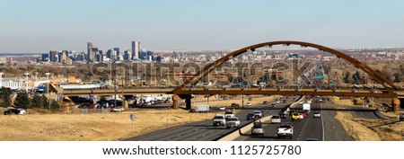 Automobile Traffic passes under a bridge that carries trains for public transit in the Denver Metro area