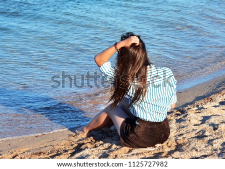 Girl sitting on the sand near the sea