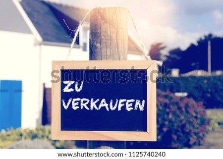 A house and a sign with the text For Sale in german