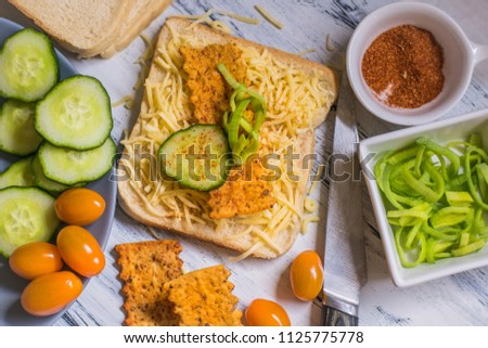 Vegetarian breakfast, toasted bread with cheese, tomatoes, leeks, cucumbers, spices and Italian spagetti chips