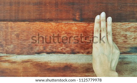 The hands are doing gestures. The background is wooden.