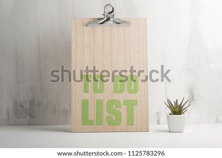 An empty wooden frame with a flower against the wall background. The concept of design and font inscriptions and image placement