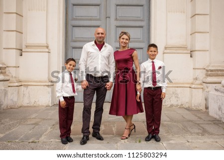 Happy family photo, parents with kids - two young boys, groomsmen posing at camera. They are guests on the wedding day of their daughter or son.