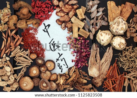 Traditional chinese herbs used in alternative medicine with calligraphy script on rice paper on dark wood background. Translation reads as chinese herbal medicine.