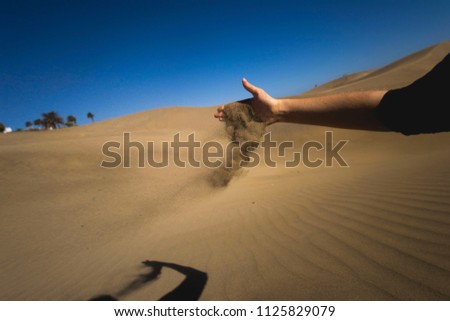Maspalomas Dunes, Gran Canaria, Canary Islands, Spain, view of sunset dunes, wind is taking the sand over, hand holding sand, falling sand, flying sand