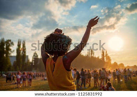 Young African American woman dancing at summer holi festival, back view Royalty-Free Stock Photo #1125831992