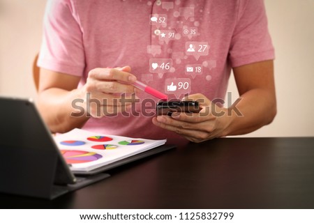 Social media and Marketing virtual icons screen concept.businessman in pink t-shirt working with smart phone and digitl tablet computer on wooden desk in modern office 