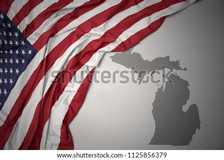 waving colorful national flag of united states of america on a gray michigan state map background.