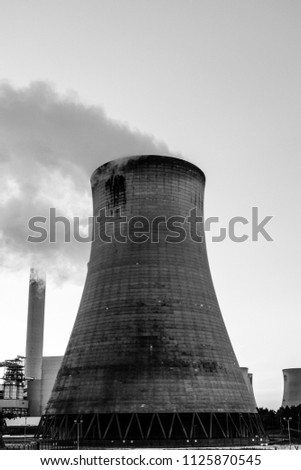 cooling tower with smoke plumes and large chimney in background